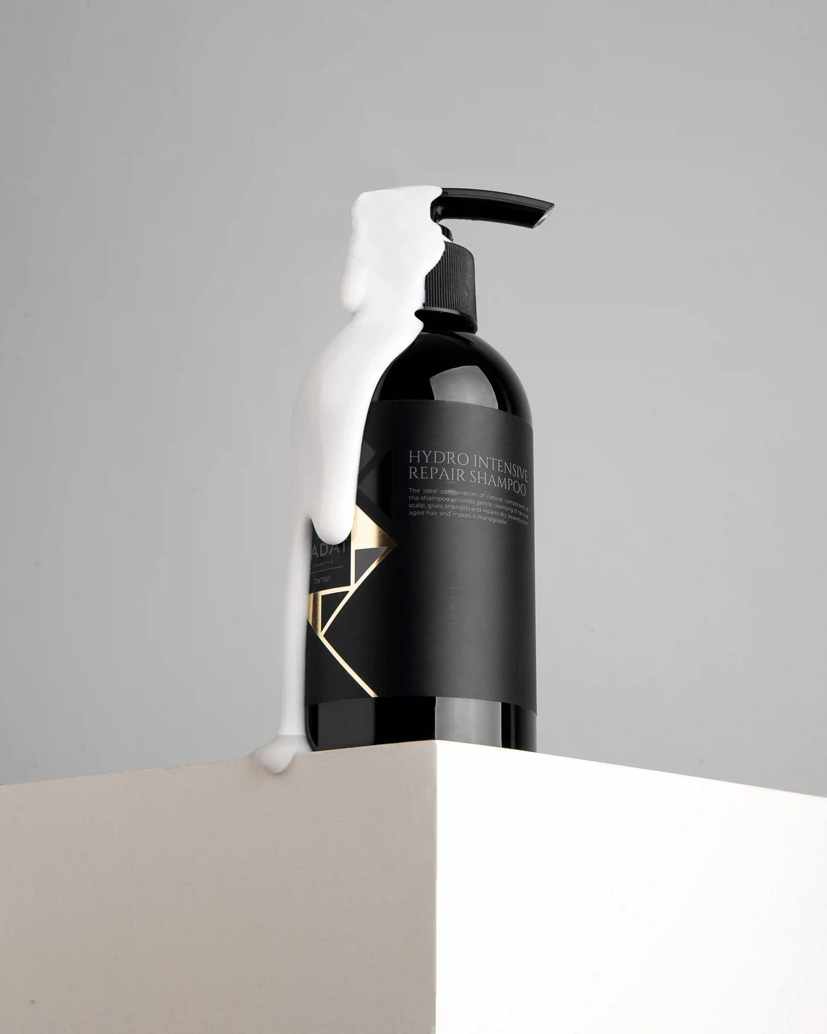 Hydro Intensive Repair Shampoo bottle with white foam drip on gray background