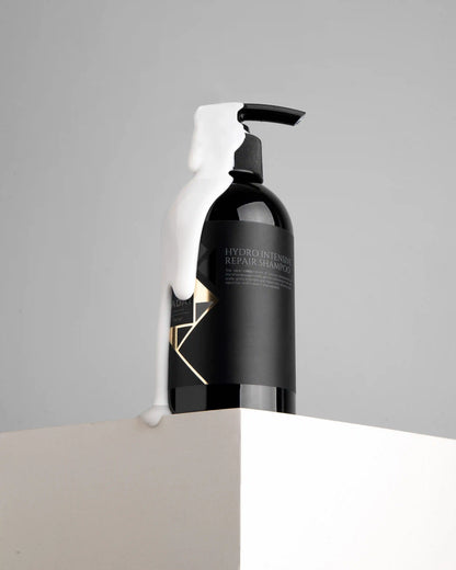 Hydro Intensive Repair Shampoo bottle with white foam drip on gray background