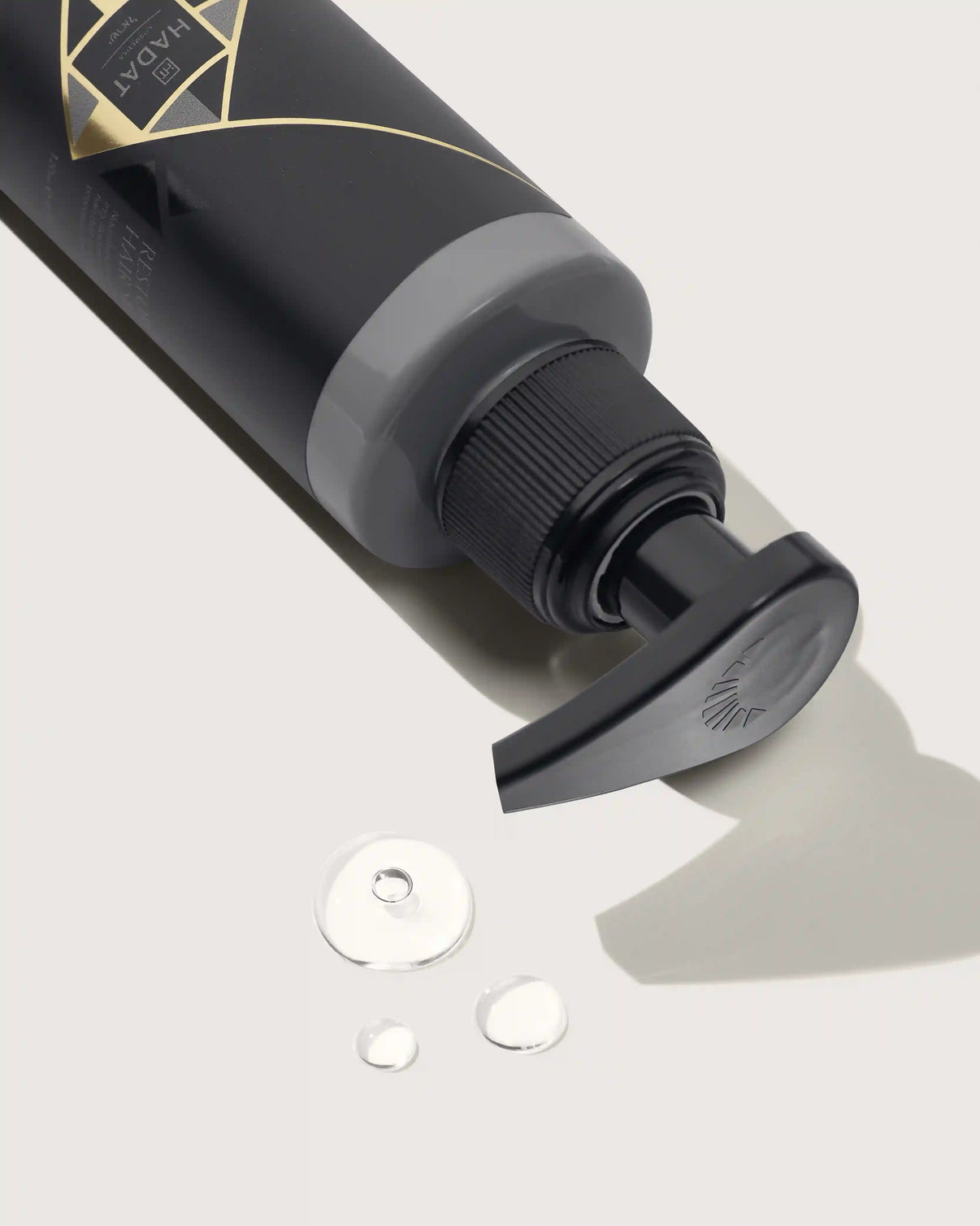 Luxury black hair care bottle with gold label and droplets