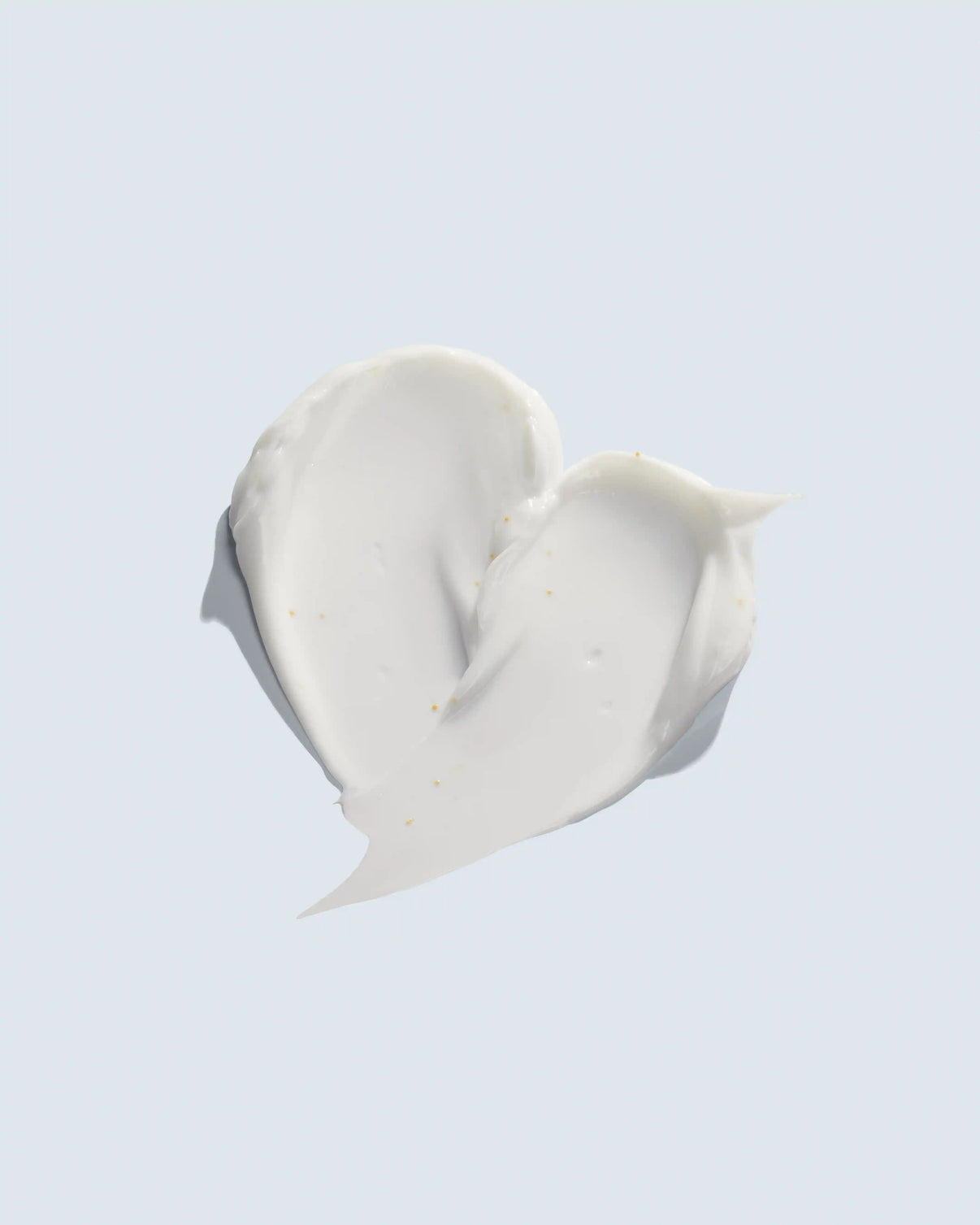 Creamy white cosmetic swatch with golden flecks on light background